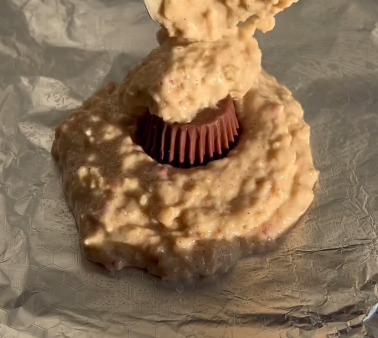 Step 1.1: Add most of the batter to a greased baking foil, then place the mini Reese’s cup (or chocolate) in the center and cover with the remaining batter