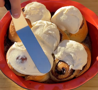 Step 5.1: Spread the frosting over the warm rolls