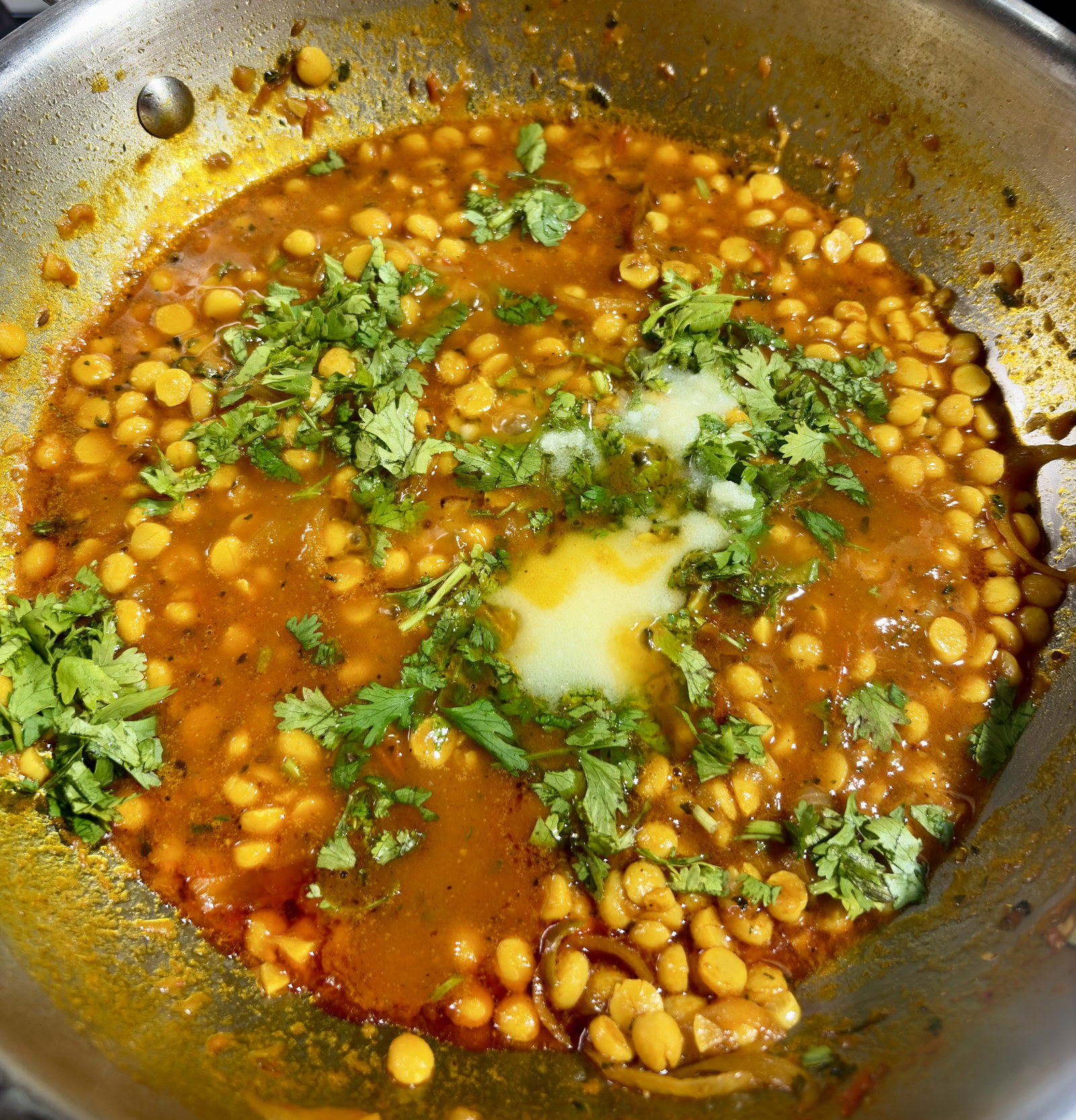 Step 5.1: Once the dal reaches the desired consistency, crush the kasuri methi between your palms and add it to the kadhai along with the garam masala, the remaining 1 tablespoon of ghee and the freshly chopped coriander