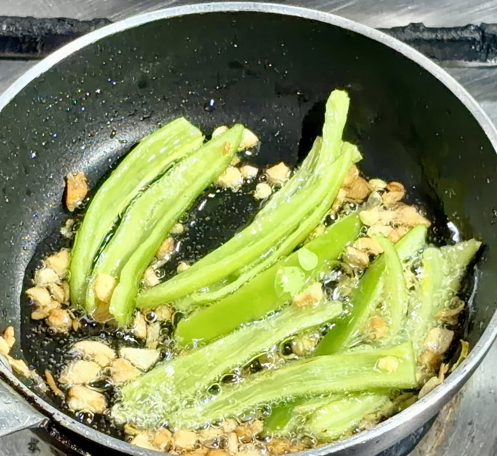 Step 5.1: Add slit green chillies and sauté for a few seconds until blistered