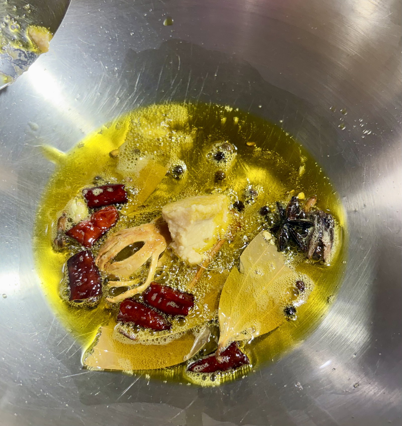 Step 2.2: Reduce the heat and add the cinnamon, cloves, black cardamom, green cardamom, mace, star anise, black peppercorns, dried red chillies, and bay leaf