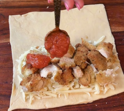Step 1.1: Layer shredded mozzarella cheese, chopped crispy parmesan chicken tenders, and a spoonful of marinara sauce onto the dough
