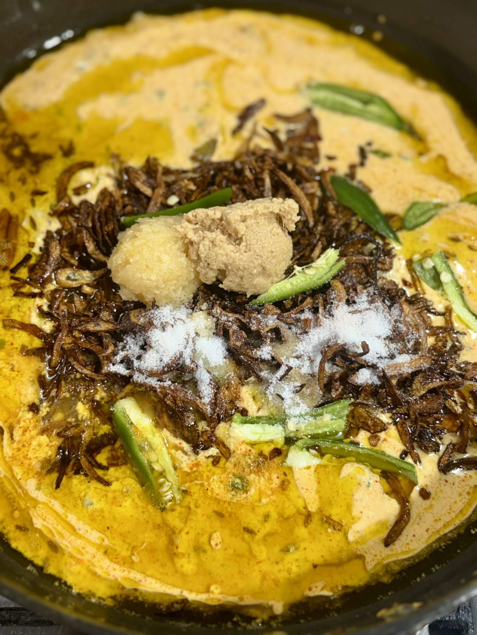 Step 5.1: Lower the heat and add curd mix, fried barista, ginger-garlic paste, green chillies, and salt