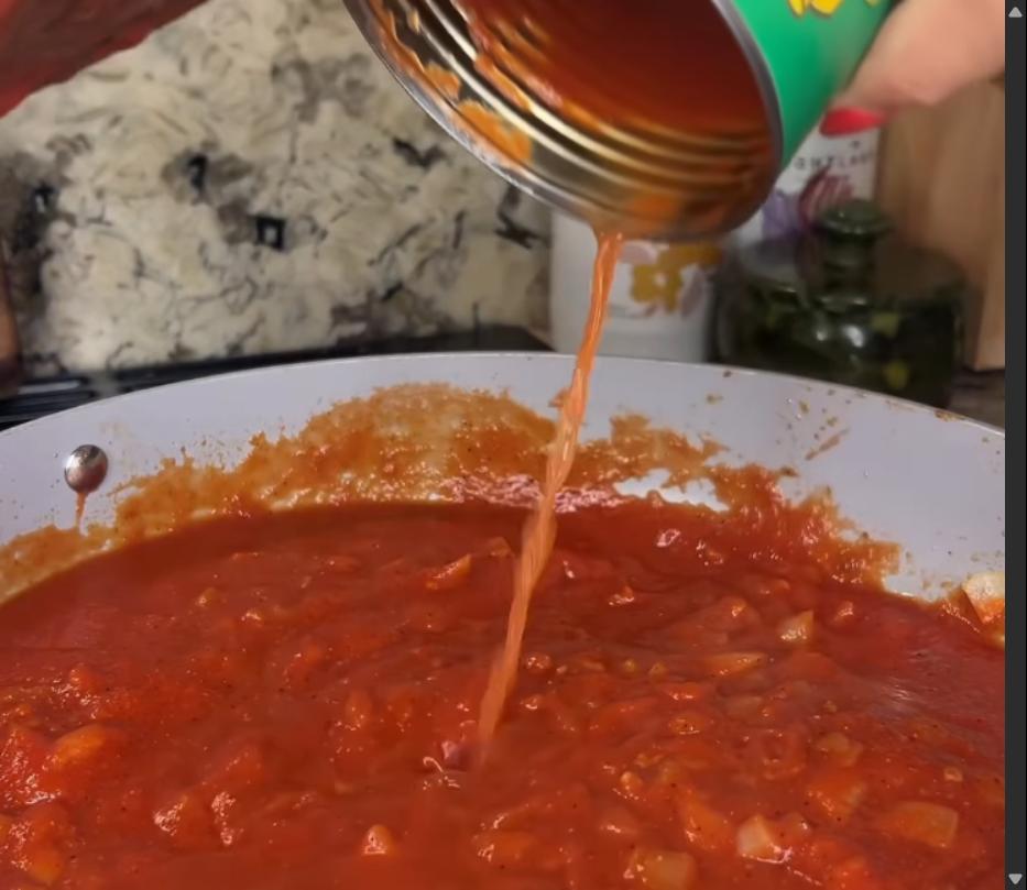 Step 2.1: Pour in the tomato puree and water, stirring to combine