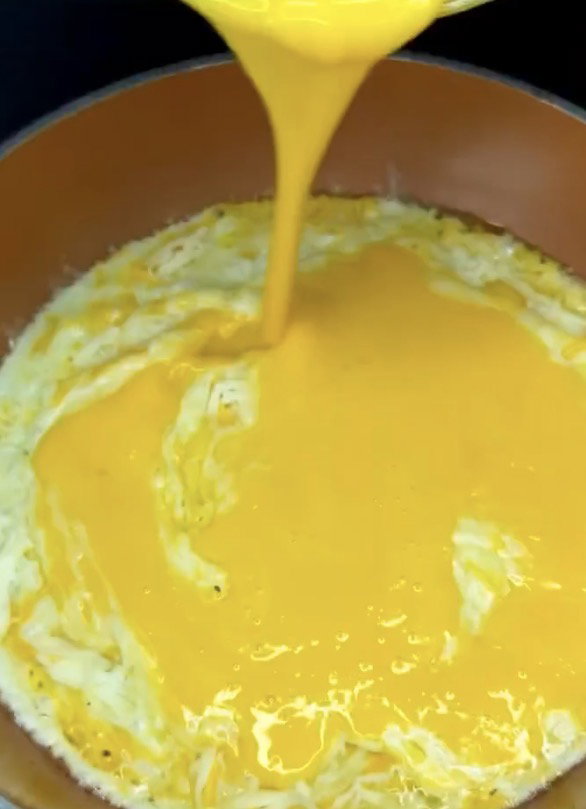 Step 1.1: Pour beaten eggs over the cheese