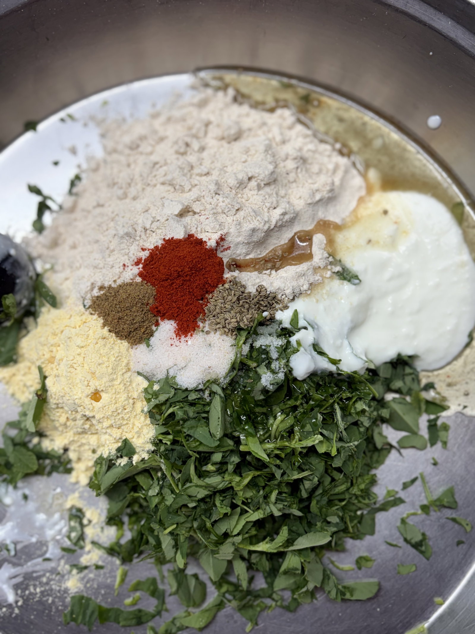 Step 1.1: एक बड़े मिक्सिंग बाउल में गेहूं का आटा, बेसन, कटी हुई मेथी, दही, तेल, मसाले और नमक डालें। हाथ से अच्छी तरह मिलाएं ताकि मेथी समान रूप से मिल जाए।