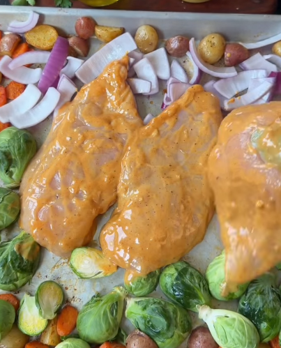 Step 1.1: Remove the sheet pan from the oven, add Brussels sprouts and onion, then nestle the chicken onto the pan