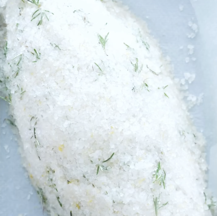 Step 3.2: Lay a thin base of the salt mixture on a tray, place the stuffed sea bass on top, and fully cover with the remaining salt mix