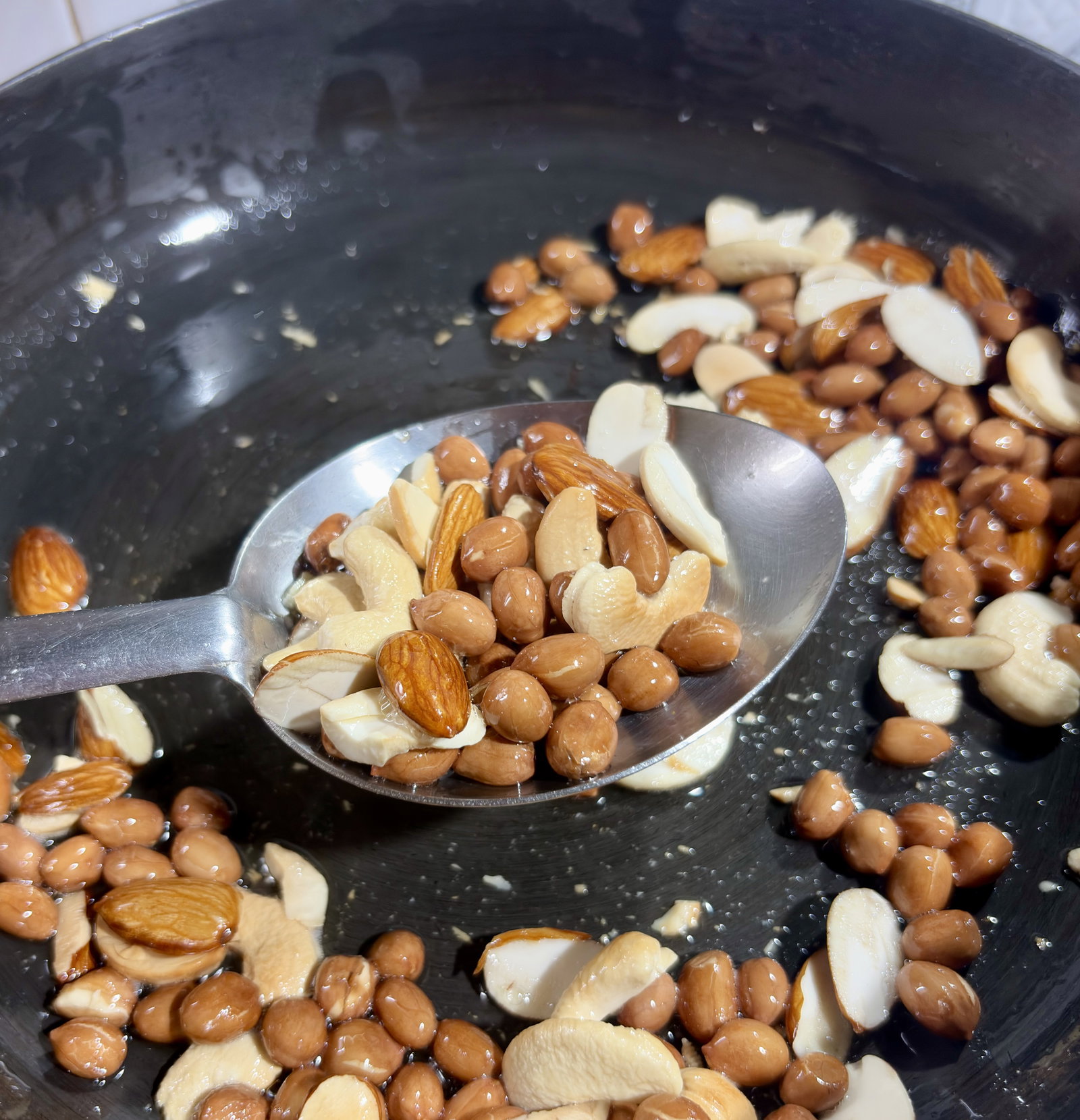 Step 2.1: Add the sliced almonds and cashews, frying for another 1-2 minutes until lightly golden