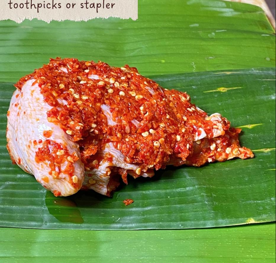 Step 4.1: Place the chicken with spices on a banana leaf, wrap it tightly, and secure with toothpicks or a stapler