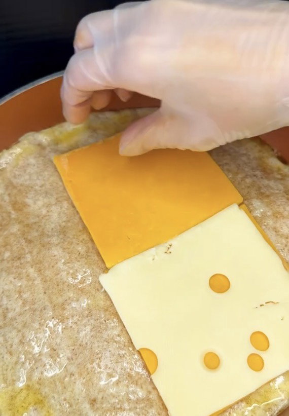 Step 1.2: Place cheddar and white American cheese slices on one half of the tortilla
