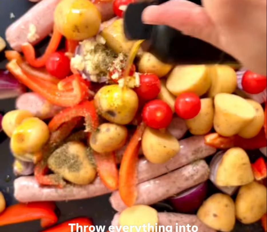 Step 1.1: Add sausages, baby potatoes, red onions, red peppers, cherry tomatoes, garlic, thyme, and black pepper to a large roasting tray and mix