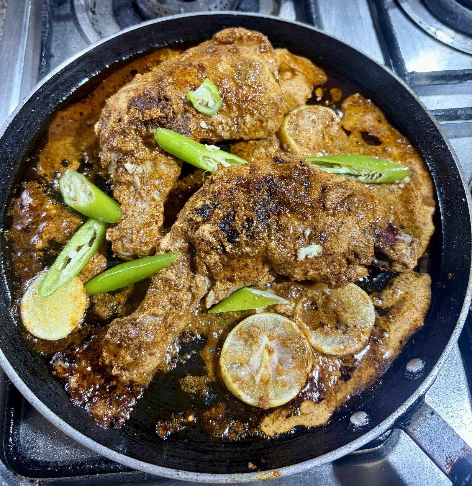 Step 4.1: Uncover the tawa and add the lemon slices and slit green chillies around the chicken