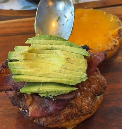Step 1.1: Layer the bottom bun with iceberg lettuce, chicken, bacon, avocado, and crispy fried onions