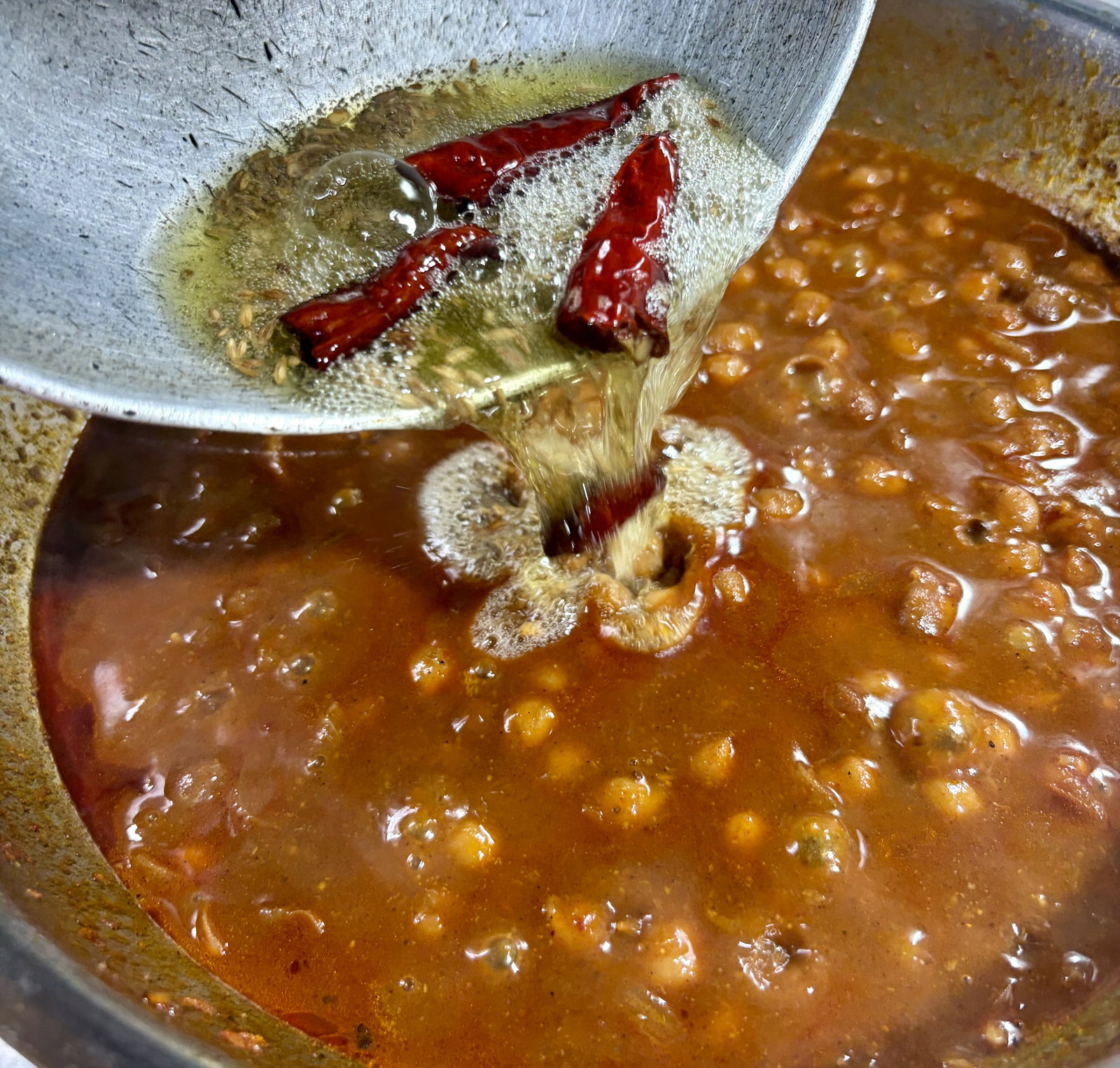 Step 3.1: Once they crackle, pour the tempering over the simmered chole