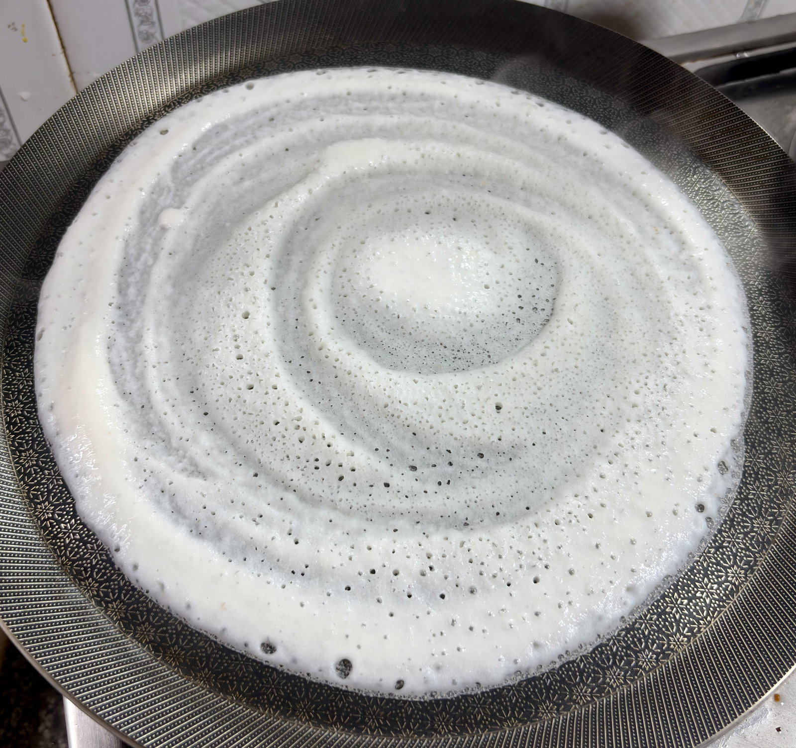 Step 3.1: Using the back of the ladle, gently spread the batter in a continuous, outward circular motion to form a thin, even layer