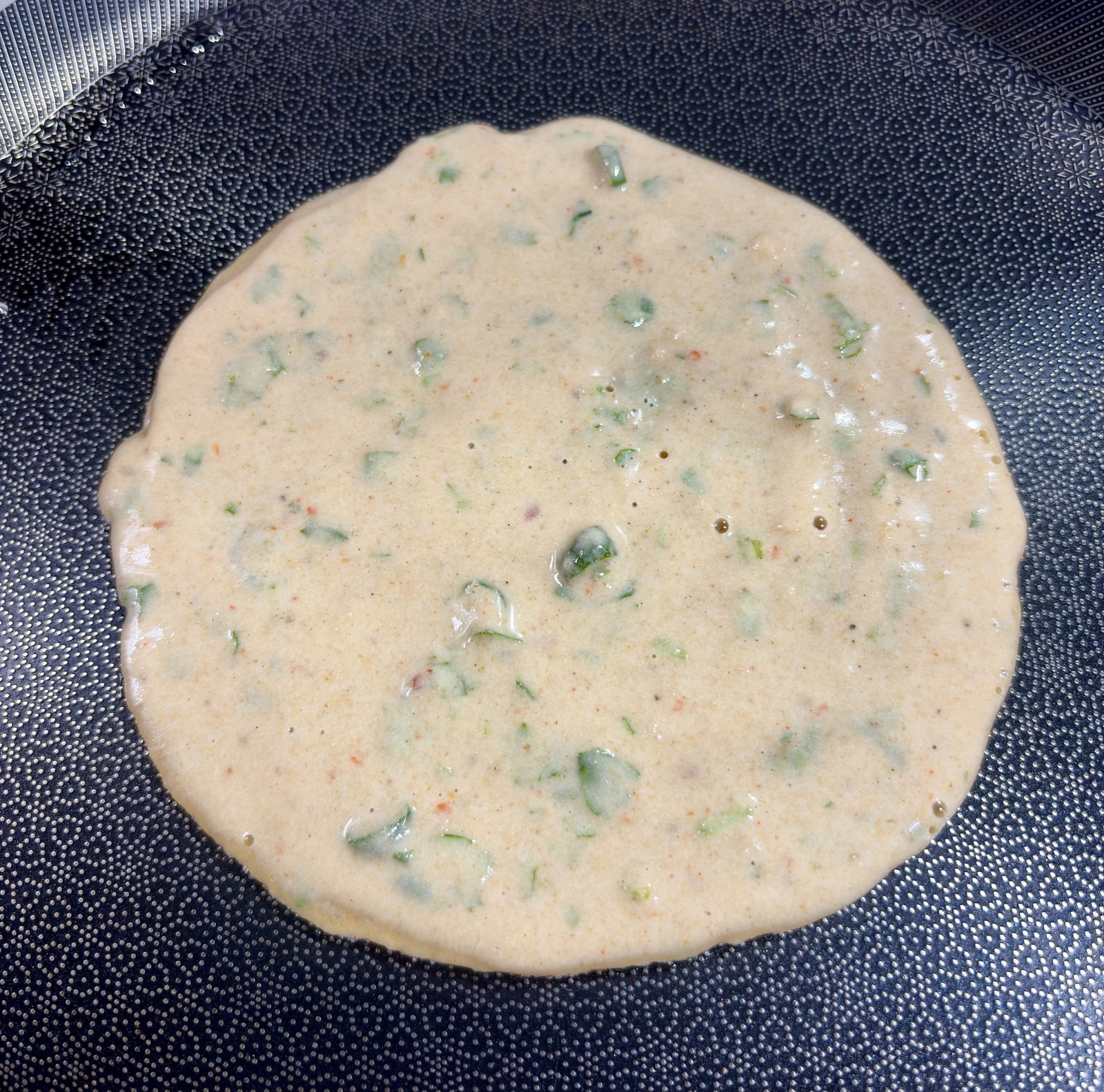 Step 1.1: **Pour & Spread: **Lower the heat and pour a ladleful of batter into the centre