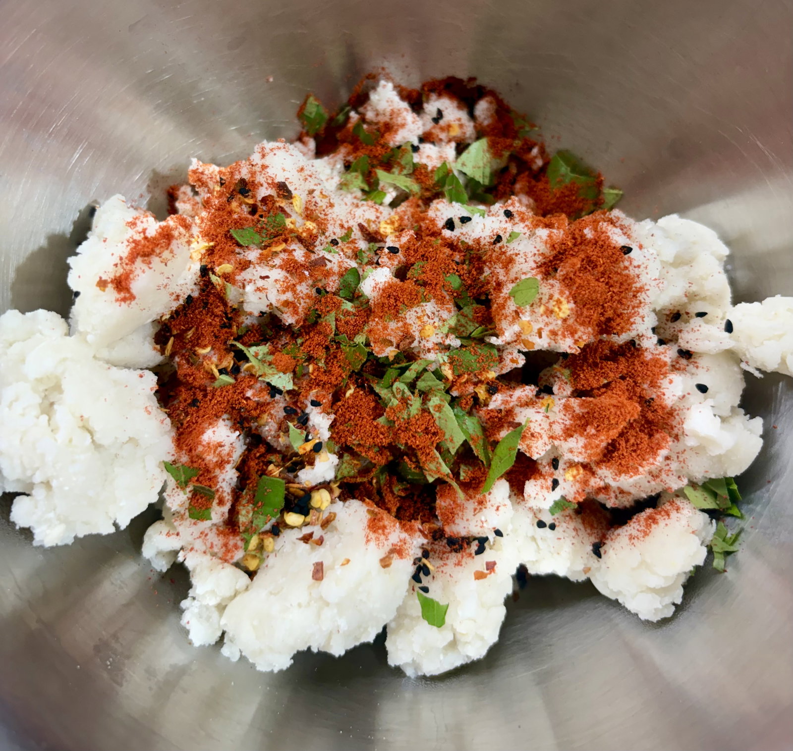 Step 2.1: Add the kalonji, red chilli flakes, Kashmiri chilli powder, chopped curry leaves, and 1 tablespoon of oil