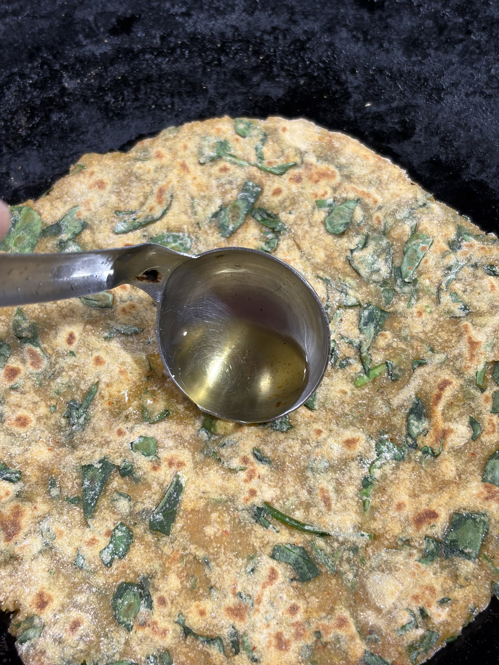 Step 3.1: पराठा पलटें, थोड़ा तेल या घी लगाएं और चम्मच से हल्के से दबाएं। दोनों तरफ सुनहरा और कुरकुरा होने तक पकाएं।