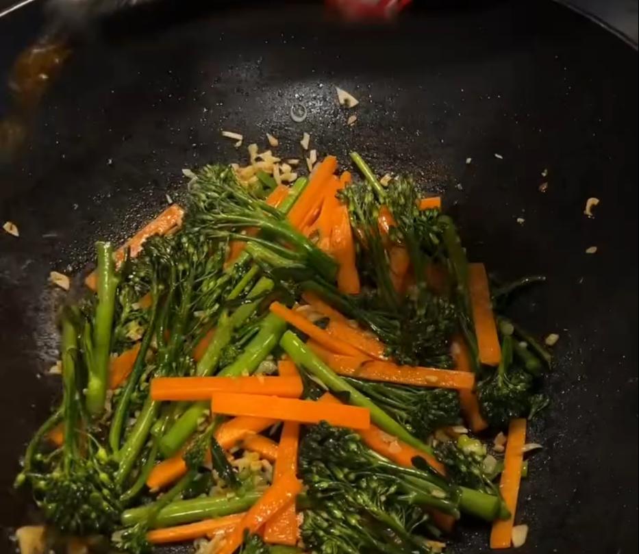 Step 4.1: Add the garlic and ginger to the wok, then the carrot and broccolini, and stir fry until just tender