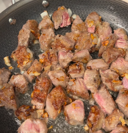 Step 1.1: Add the steak bites to the sautéed onions and garlic and sear the edges