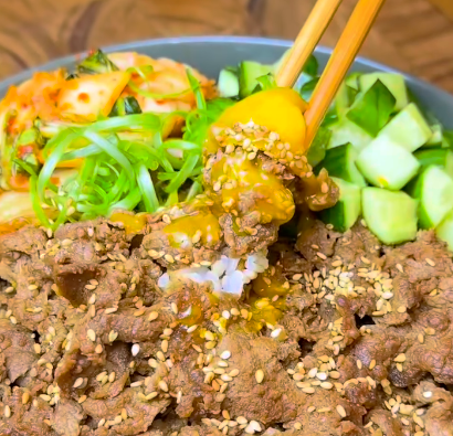 Step 1.1: In a bowl, add rice, then top with bulgogi, kimchi, cucumber, a raw egg yolk (or fried egg), green onion, and sesame seeds
