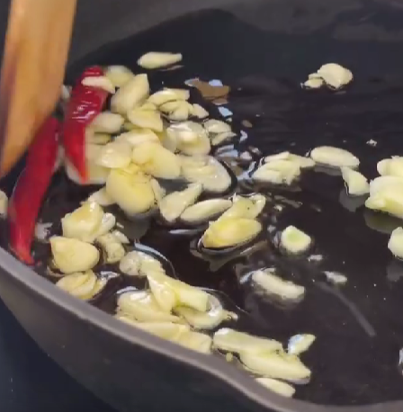 Step 2.1: Heat olive oil in a pan on low heat and fry chopped garlic and chilies until golden