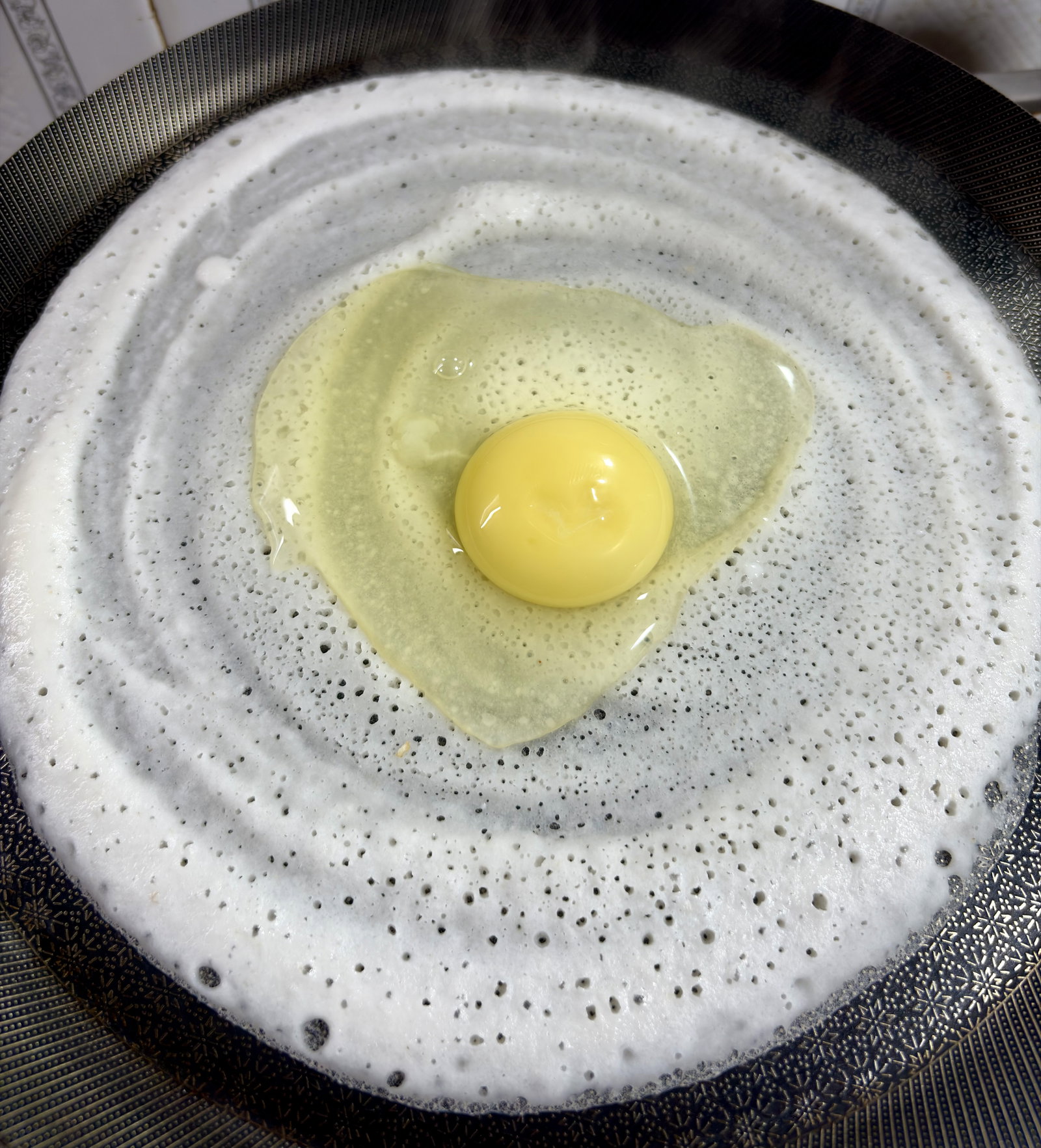 Step 4.1: Immediately crack an egg directly over the centre of the dosa