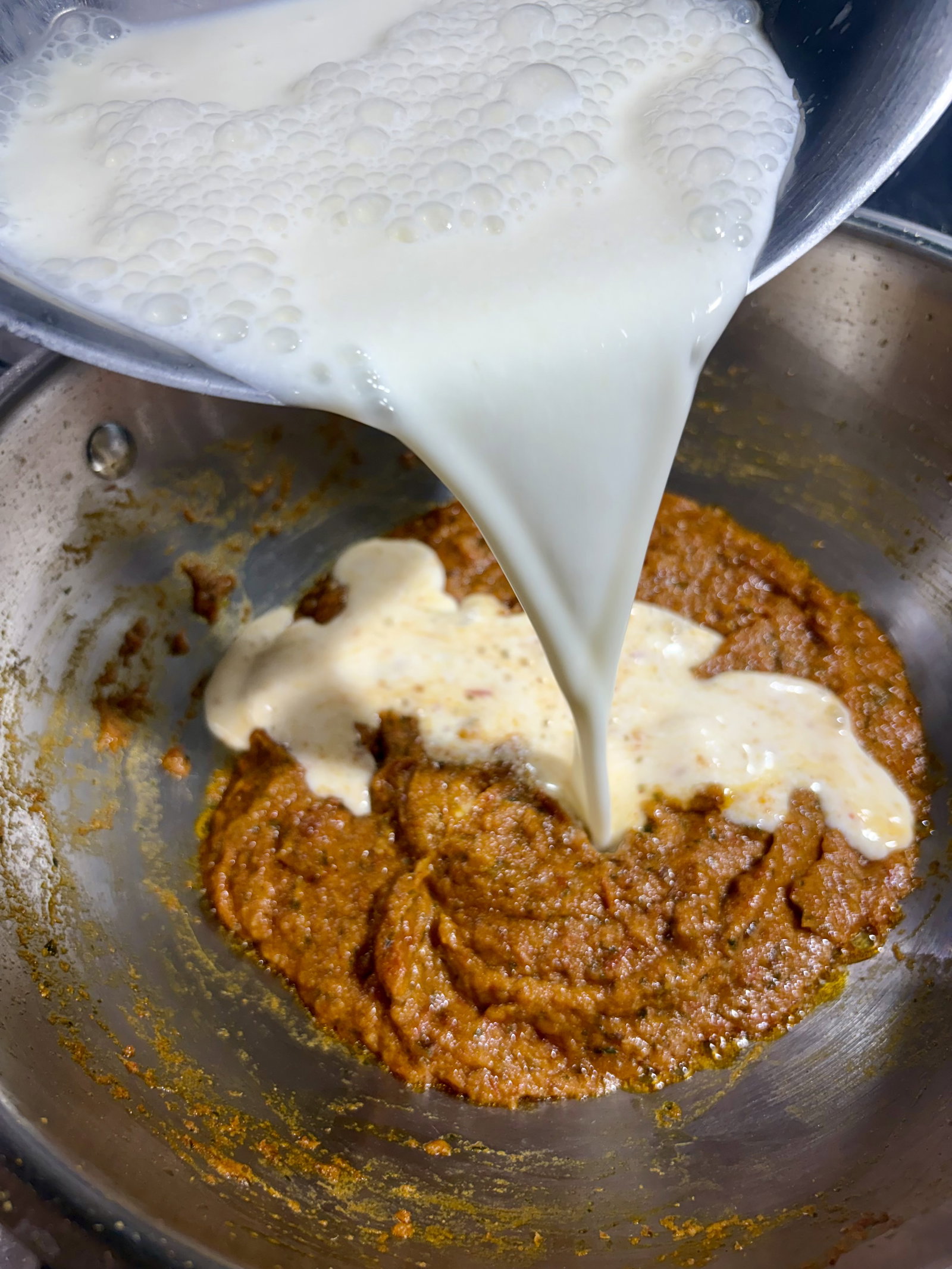 Step 4.1: Keep the heat low and slowly pour in the prepared curd mixture, stirring continuously until the oil surfaces on top