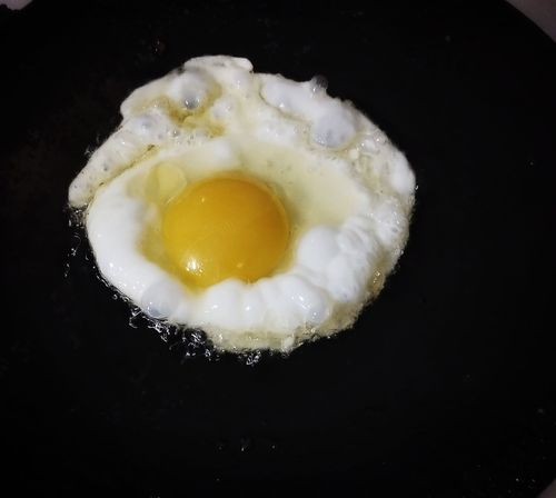 Step 1.1: When the oil becomes hot, crack open one egg and fry until the edges become crispy