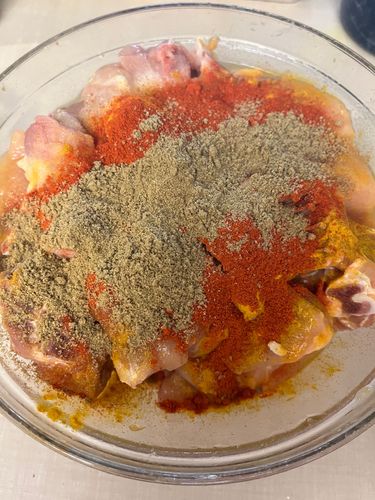 Step 1.1: Transfer the chicken pieces to a mixing bowl and add salt, red chilli powder, coriander powder, cumin powder, and thick curd