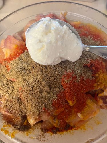 Step 1.2: Transfer the chicken pieces to a mixing bowl and add salt, red chilli powder, coriander powder, cumin powder, and thick curd