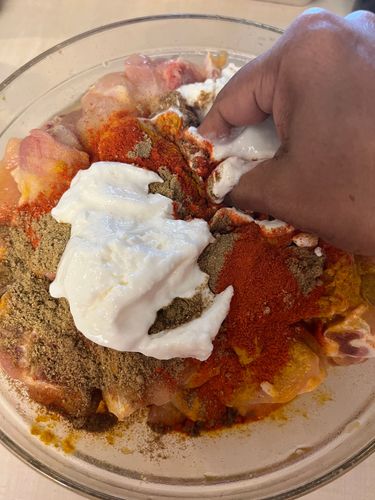 Step 1.3: Transfer the chicken pieces to a mixing bowl and add salt, red chilli powder, coriander powder, cumin powder, and thick curd