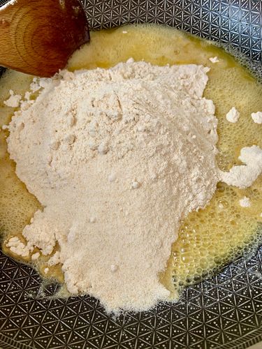 Step 4.1: In the same pan, add the whole wheat flour (atta) and semolina (sooji)